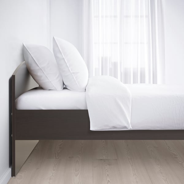 A modern, rounded-edge bed with white bedding, showing sturdy frame and storage space underneath.