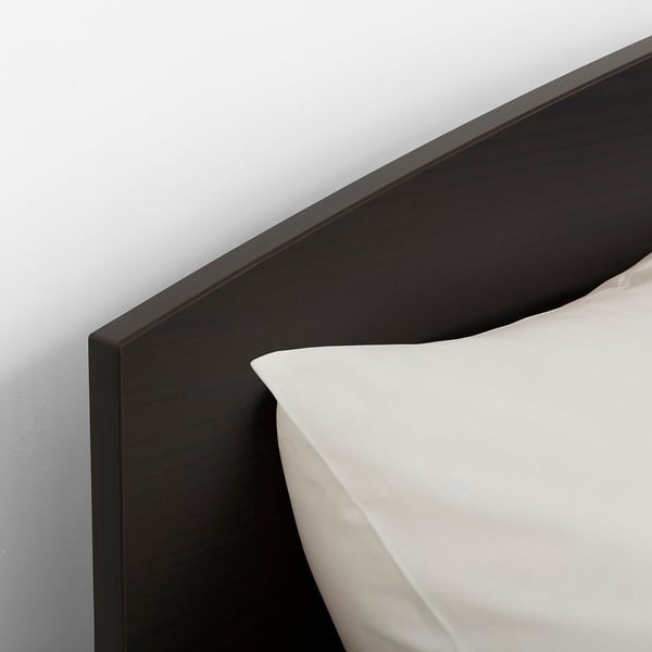 Black bed frame with smooth, rounded corners and white bedding, showcasing quality design and craftsmanship.