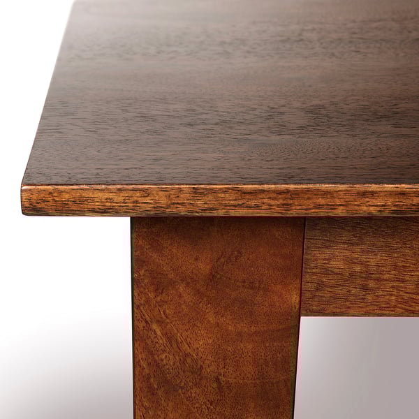Dark wooden table corner, gleaming with polished finish, showcasing high-quality craftsmanship.
