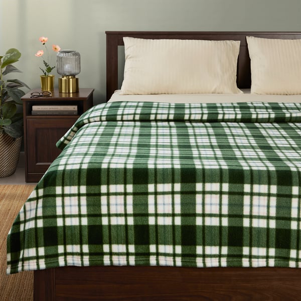 Cosy green & white chequered ODENSLÄTA blanket on bed, made from recycled polyester, fits perfectly, adding warmth and style.