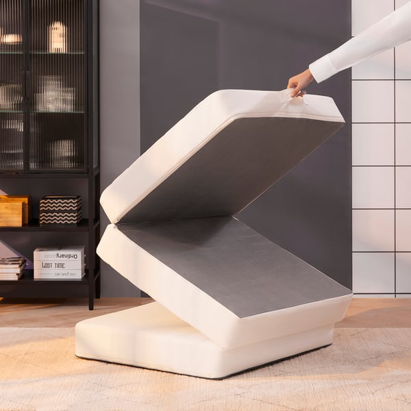 A person opens a multifunctional white pouffe transforming it into a guest bed.