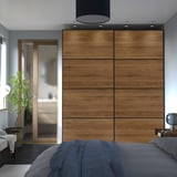 Modern bedroom with large PAX wardrobe, blue bedding, glass door, and plant.