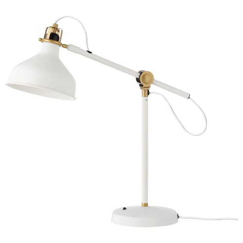 A white, adjustable RANARP desk lamp with golden metal accents. It has a round base, a long arm, and a movable shade for directed light.