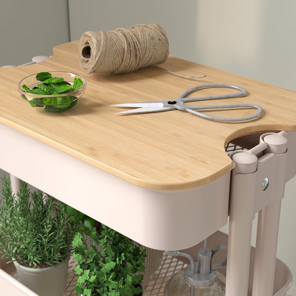 RÅSKOG kitchen trolley with bamboo cutting board. Contains herbal bowl, scissors, and twine, set against a grey wall.