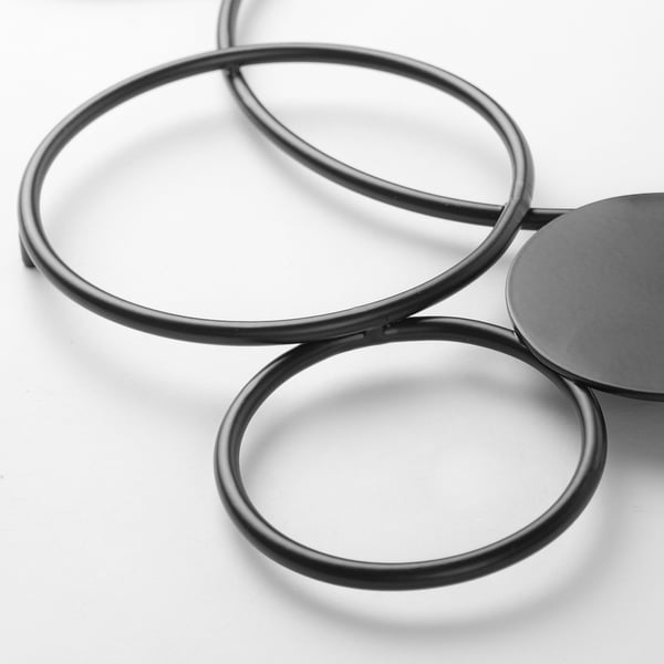 Black circular metal wall decoration, gleaming and modern, part of the RÖDSISKA series, mounted on a white wall.