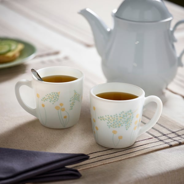 Floral mugs with tea next to teapot