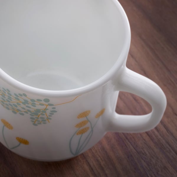 Close-up of a white mug with floral design, showing clear, smooth surface and sturdy handle.