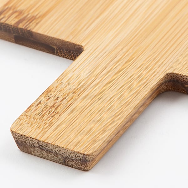 Two light brown bamboo cutting boards lying on a white surface, showing smooth, polished edges and a natural wood grain texture.