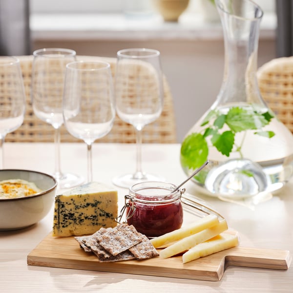 SNEDNÄBB bamboo cutting board, rectangular, natural colour. Holds cheese, crackers, and jam. Smaller than wine glasses, larger than a coaster.