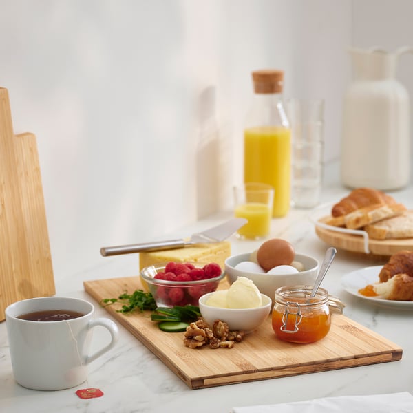 Bamboo cutting board with raspberries, butter, jam, walnuts, coffee.