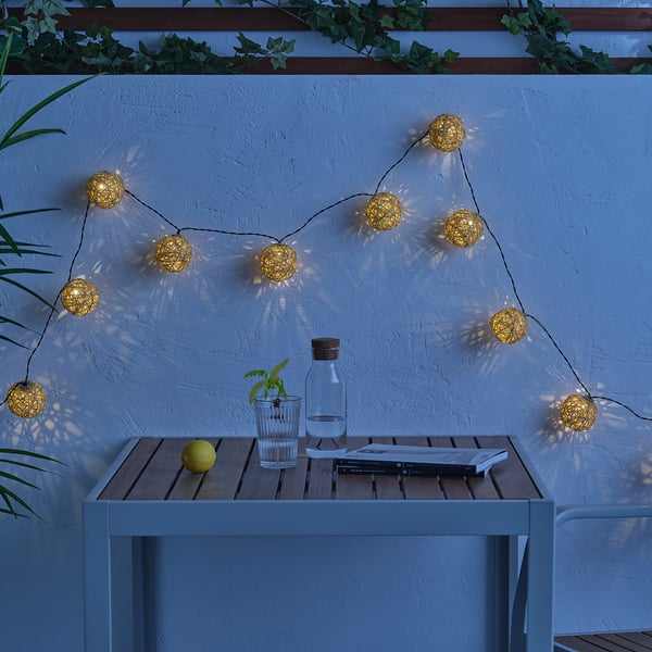 Spherical SOLVINDEN lights hang on wall, illuminating table with lemon, glass, and magazine.