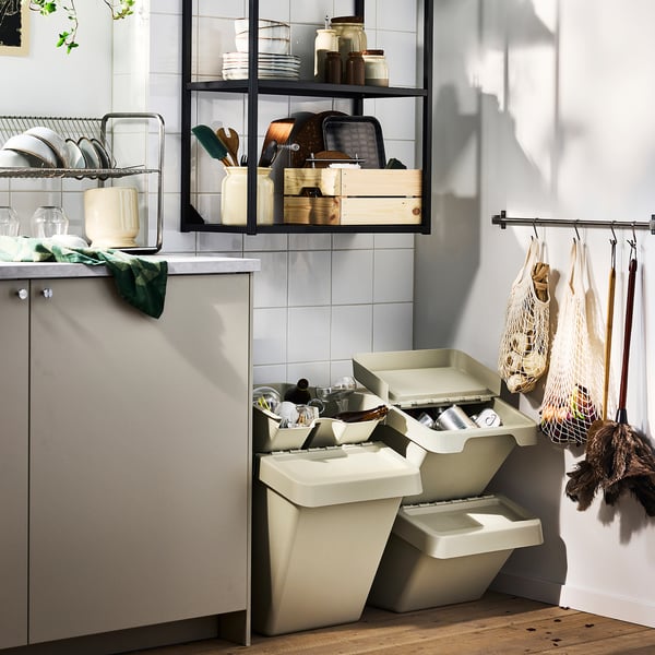 Kitchen corner with sort and recycle bins, hanging utensils, and organised shelves.