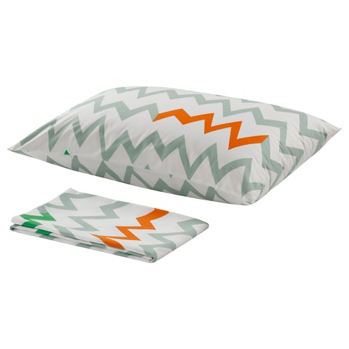 Image displays a white pillow and folded sheet set with green, orange, and white zigzag patterns. The materials are 100% cotton.