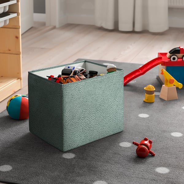 Large STJÄRNSKOTT green dotty box stores toys, fits well near shelves, handy for playroom.