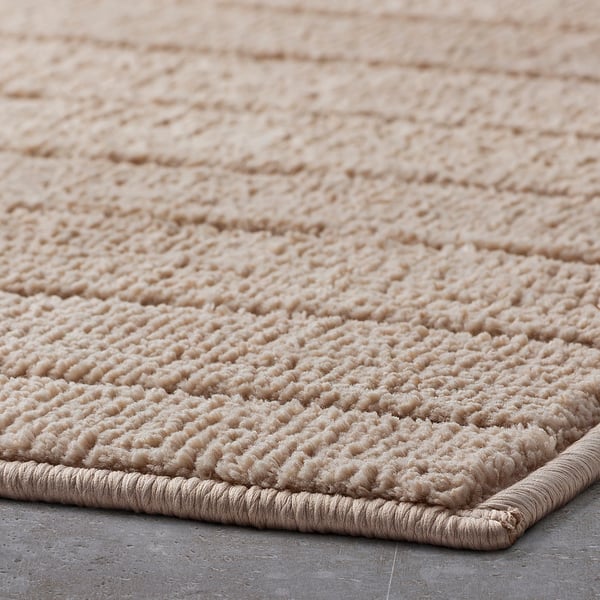 Close-up of a soft, textured beige bath mat with a quick-drying surface and non-slip backing.