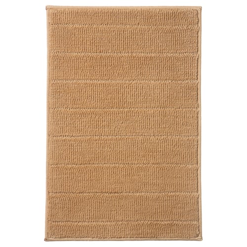 A beige-colored rectangular bath mat named TIDNINGSBUD, made from recycled polyester, offering a soft and quick-drying surface.