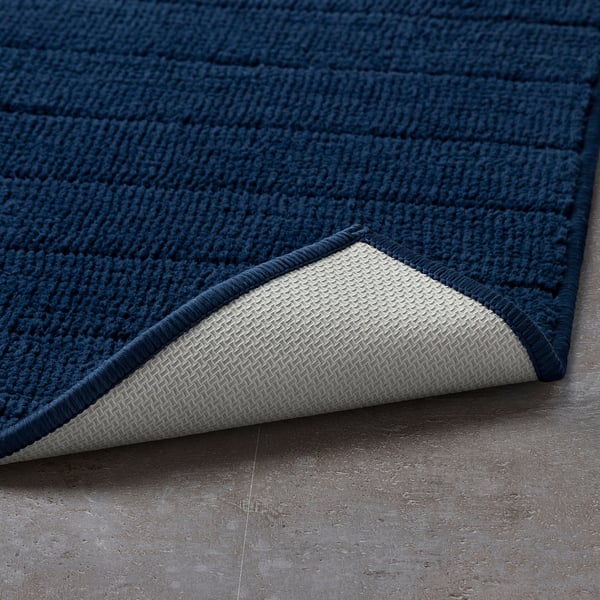 Blue bath mat with textured surface and white underside for grip.