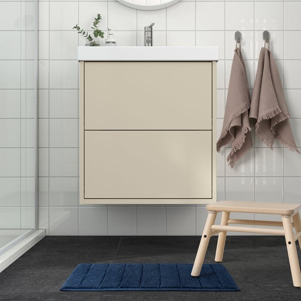 Modern bathroom with dark blue TIDNINGSBUD mat under wooden bench, non-slip shower surface.