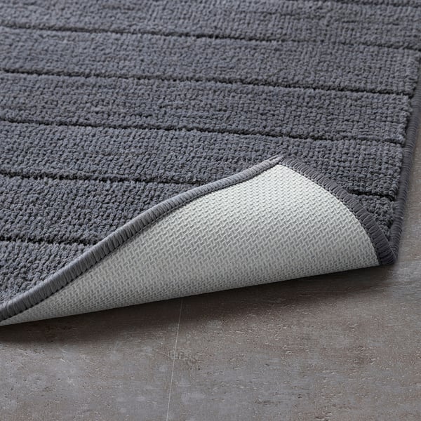 Grey bath mat with textured stripes and soft pile. Latex backing prevents slipping.