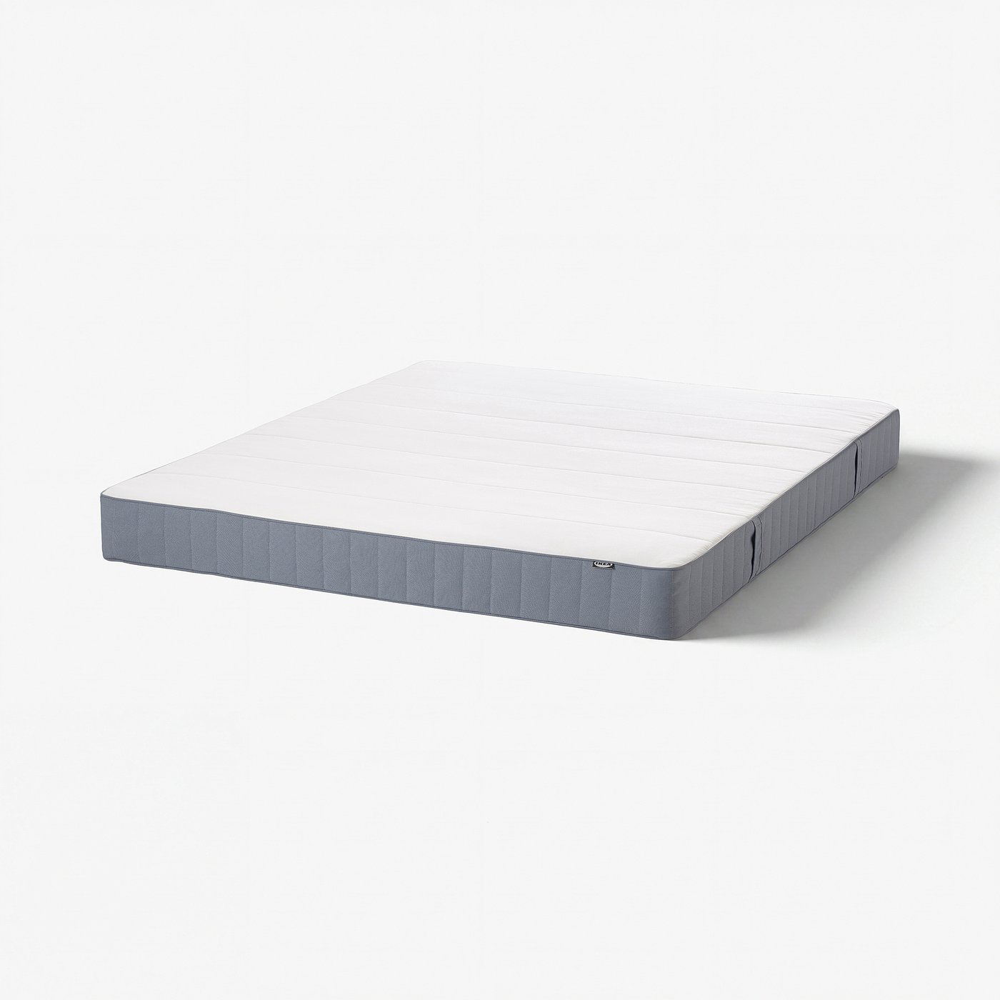 White VESTMARKA mattress, rectangular, firm, with grey sides and foam top layer.
