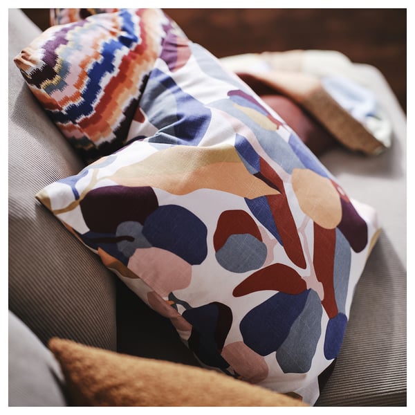 Abstract patterned pillow covers in white with multicolor spots, two on a couch, made from cotton.