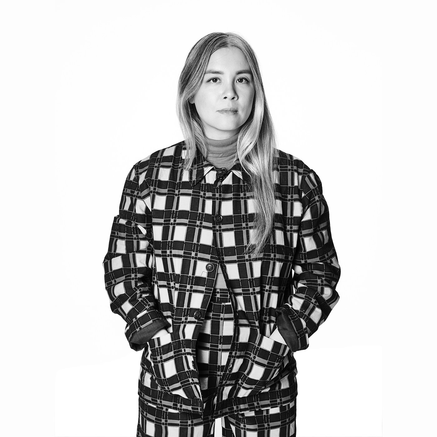 Black and white portrait of the designer in a plaid outfit.