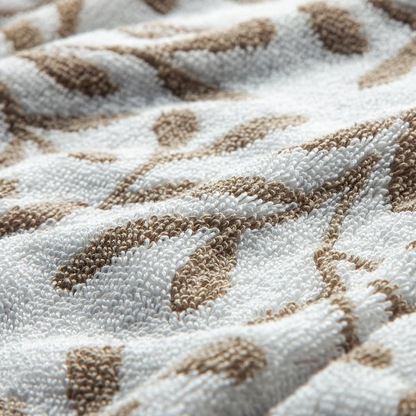Close-up of luxurious, plush cotton towel with intricate leaf pattern, showcasing high-quality weave and soft texture.