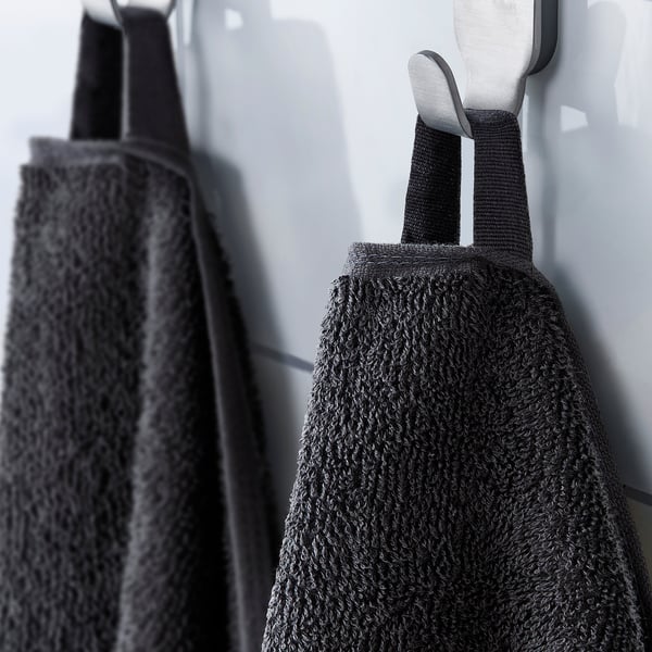 Black towels hanging on hooks with loops for easy hanging.