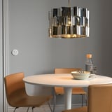 Sala da pranzo moderna con tavolo rotondo, quattro sedie, grande lampada cilindrica ÄLVSTARR sopra.