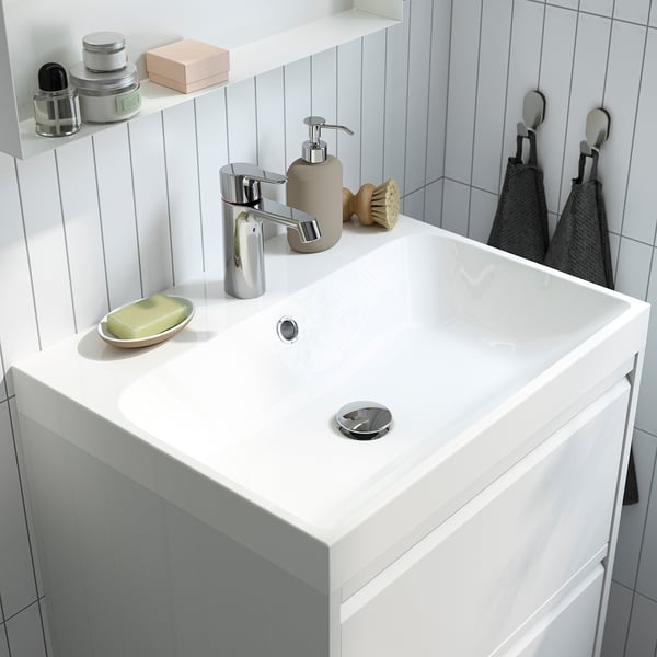 Moderno lavandino da bagno bianco con rubinetto cromato, sapone e ganci per asciugamani.