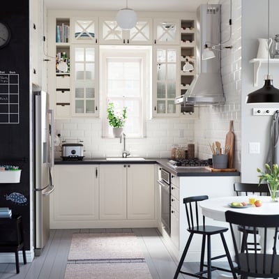 Cucina moderna con armadi bianchi, sedie nere, elettrodomestici in acciaio inossidabile e un tappeto.