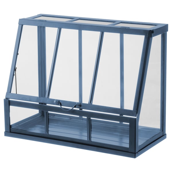 Una mini serra ÅKERBÄR grigia con struttura in metallo e lati in plastica trasparente, progettata per la crescita di piante in interni.