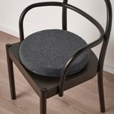 Sedia moderna con sedile rotondo e imbottito e braccioli curvi, che offrono comfort e stile.