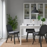 Accogliente sala da pranzo con cuscino per sedia grigio, vicino alla libreria, lampada a luce calda.