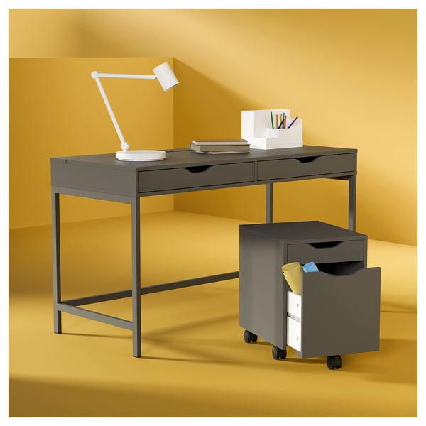 Scrivania moderna ALEX grigio scuro con cassetti, lampada, libri e schedario mobile.