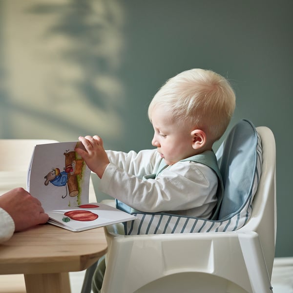 Bambino in seggiolone, lettura con adulto, su cuscino gonfiabile reversibile per il supporto.