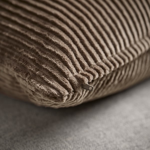 Primo piano di un morbido cuscino a righe in morbido velluto a coste con zip nascosta, che ne mette in risalto la texture accogliente.
