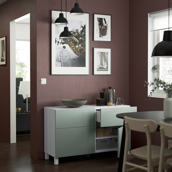 Moderna zona pranzo con credenza BESTÅ, dotata di ripiani regolabili e cassetti con apertura a pressione incorporata, opere d'arte montate a parete e lampade a sospensione.