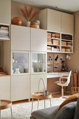 Home office moderno con i mobili contenitori BESTÅ: armadi chiari, ante in vetro, tappeto strutturato e decorazioni minimaliste.