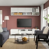 Soggiorno moderno con pareti rosse, divano grigio, tv su supporto bianco con mensole e pensile.