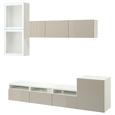 Un mobile porta tv BESTÅ bianco e beige con ripiani, armadi e cassetti, progettato per organizzare ed esporre le apparecchiature multimediali.