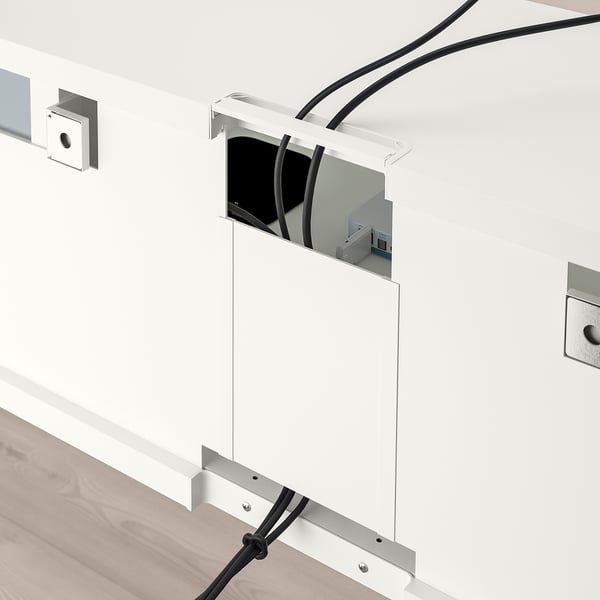 Mobile tv bianco con ripiani regolabili e passacavi, cavi a vista instradati attraverso le fessure posteriori e inferiori.