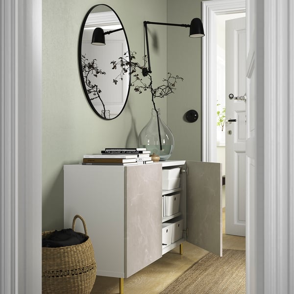 Ingresso moderno con contenitori BESTÅ, ripiani regolabili, ante con chiusura ammortizzata e oggetti decorativi.