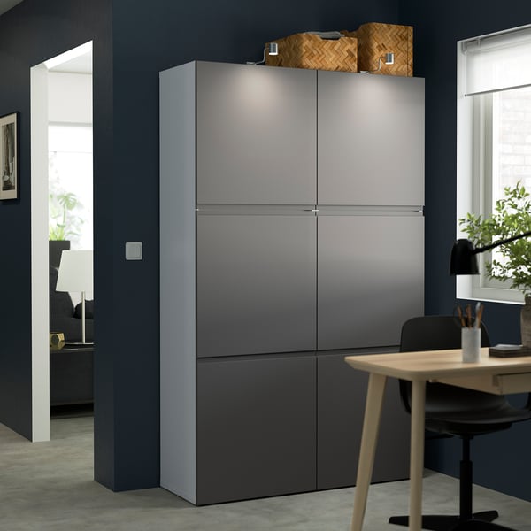 Moderno mobile contenitore grigio BESTÅ, alto e sottile, adatto alla scrivania e alla sedia dell'ufficio, con cestini intrecciati sulla parte superiore.