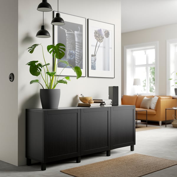 Credenza BESTÅ con piante, libri, ciotola, altoparlante, luci e arte. Divano arancione, tappeto di iuta, soggiorno luminoso.