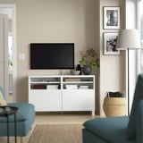 Soggiorno moderno con mobile tv BESTÅ, tv a schermo piatto, divano turchese, lampada e quadri incorniciati.