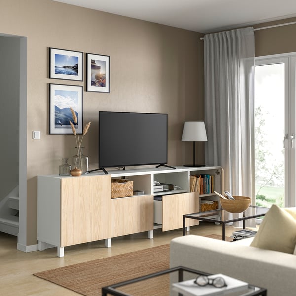 Soggiorno contemporaneo con panca tv BESTÅ marrone chiaro, tv a schermo piatto, foto incorniciate, lampada e libri.