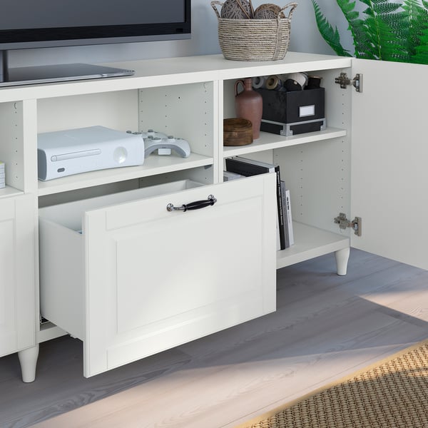 Porta tv BESTÅ bianco con cassetti aperti e ripiani per console di gioco, telecomandi, vasi e scatole portaoggetti.