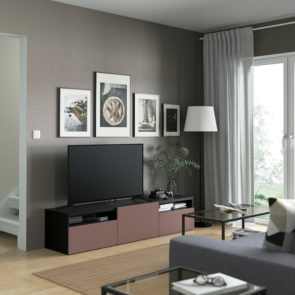 Soggiorno moderno con mobile tv BESTÅ, tv a schermo piatto, stampe d'arte e cassetti portaoggetti. Tende a figura intera, tavolino in vetro e divano grigio.