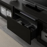 Porta tv nero con cassetto aperto, ante in vetro remote-friendly e gestione dei cavi.